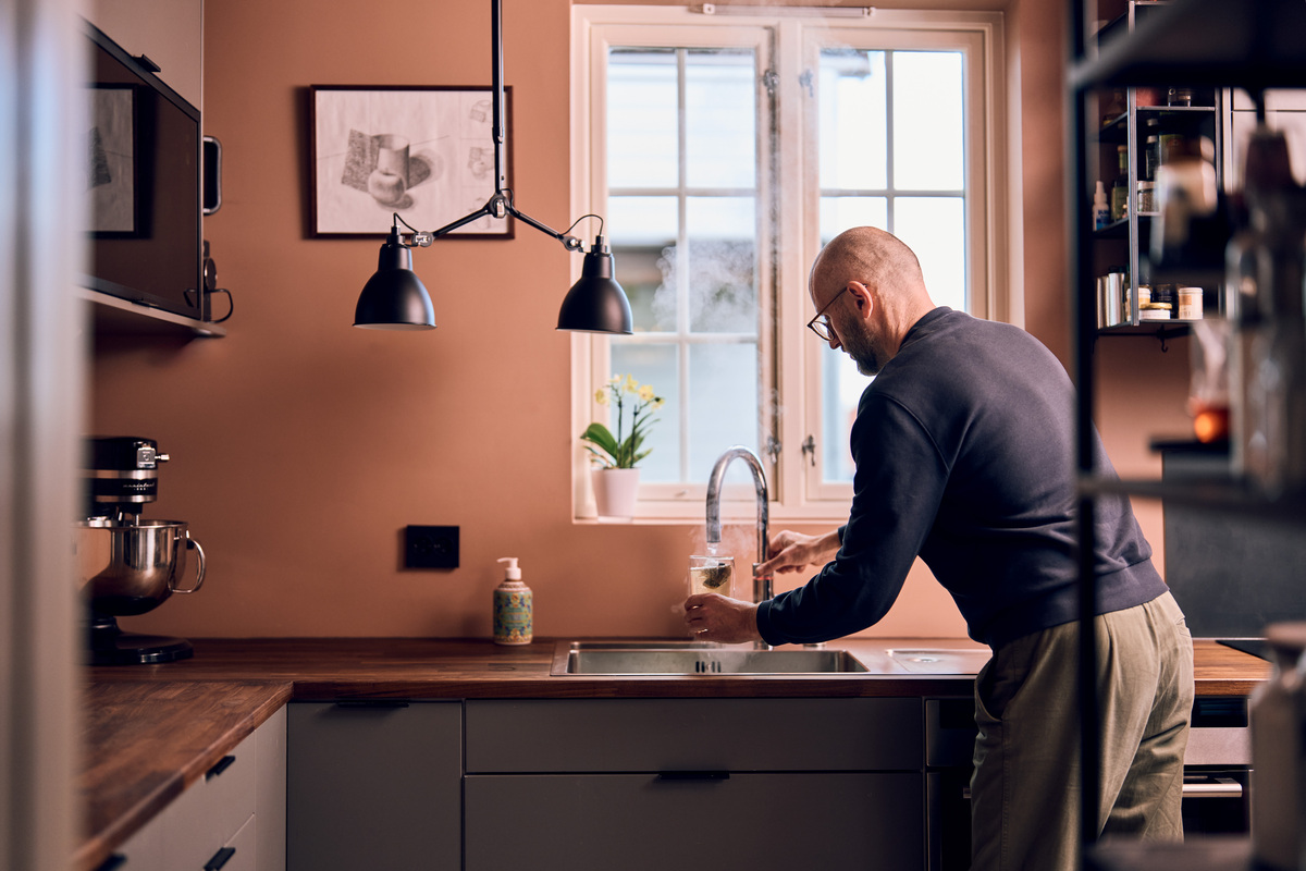 Mann tapper varmt vann fra kjøkkenkrana